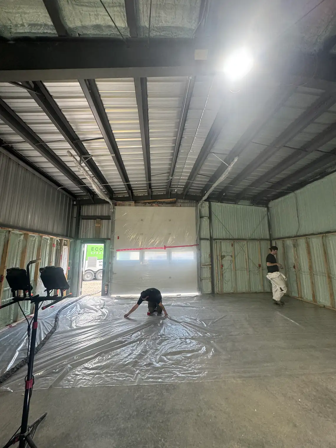 The inside of a steel shop with the walls already sprayed and the ribbed steel roof deck still bare overhead