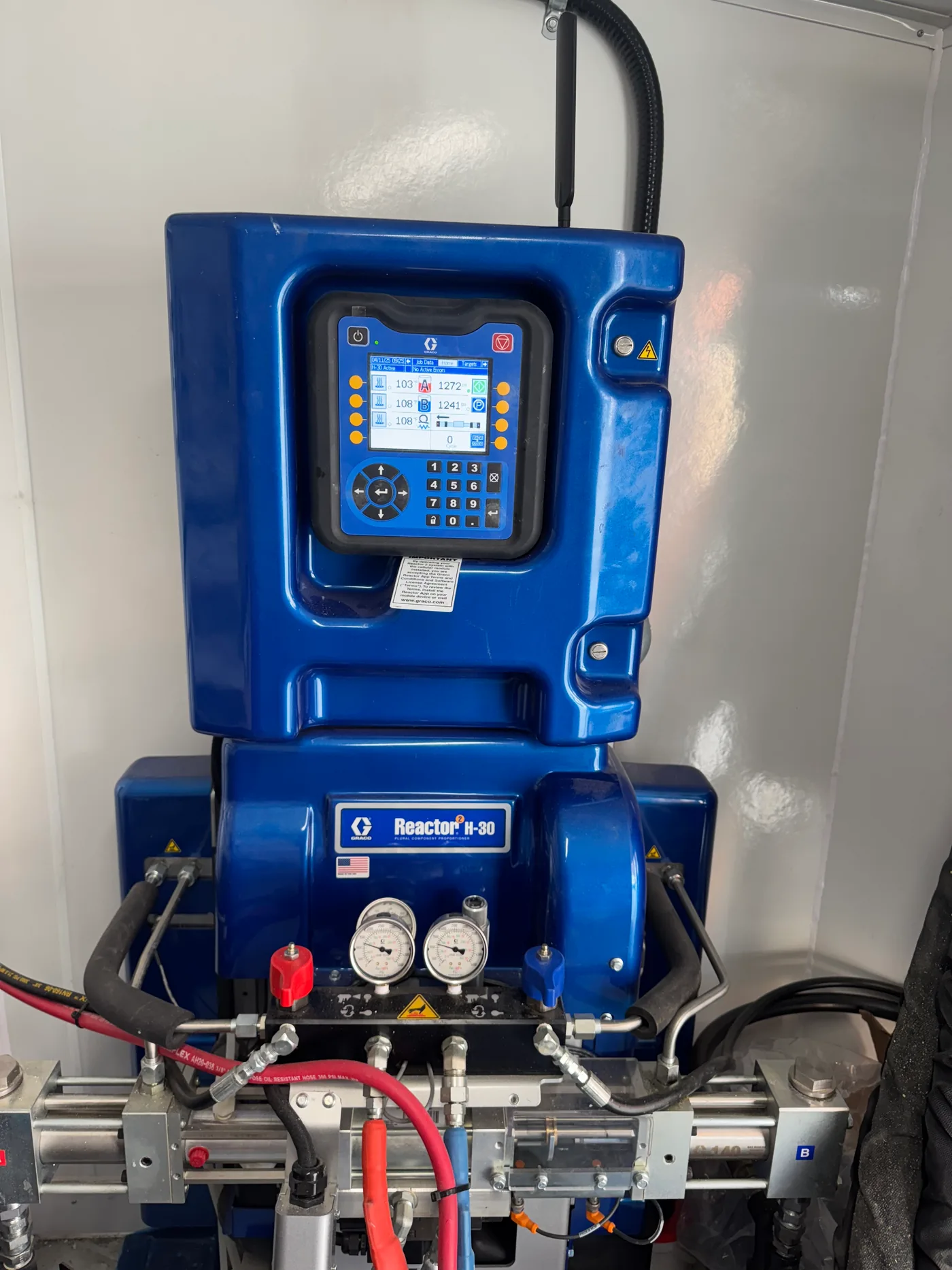 Graco Reactor H-30 proportioner inside the EcoSeal spray foam rig, showing the digital control display and heated hose lines.